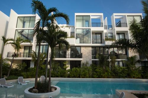 an apartment building with a palm tree in front of a swimming pool at Anah Suites Tulum by Sunest in Akumal
