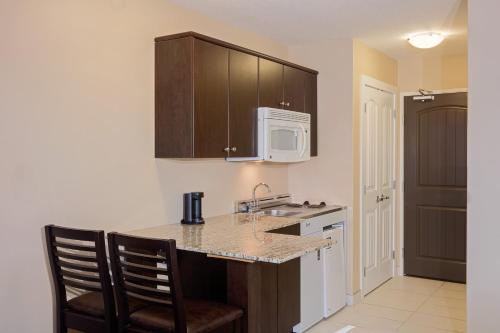 a kitchen with a counter and a sink and a microwave at Ramada by Wyndham Cold Lake in Cold Lake