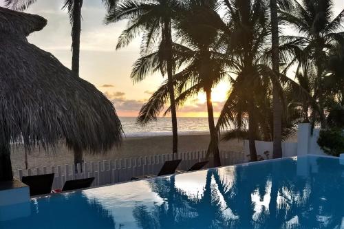 a swimming pool next to a beach with palm trees at Villa Rincon del Mar & Villa Rincon de las Morenas in Coyuca