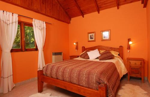 1 dormitorio con 1 cama con paredes y ventanas de color naranja en Estancia Don Jose- GuenGuel, en Río Mayo