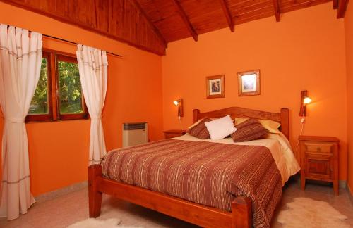 een slaapkamer met een bed met oranje muren en ramen bij Estancia Don Jose- GuenGuel in Río Mayo