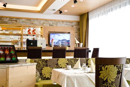 Un restaurante con una mesa y sillas y un bar. en Hotel Garni Arosa, en Ischgl