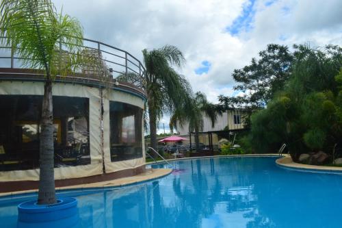 a swimming pool with a palm tree next to a building at Paraiso Termal in Federación