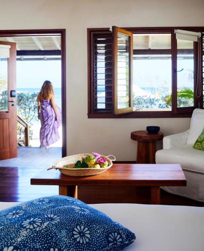 a woman walking into a room with a bowl of fruit on a table at GoldenEye in Oracabessa