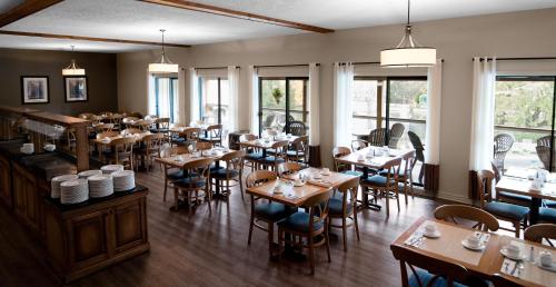 ein Restaurant mit Holztischen, Stühlen und Fenstern in der Unterkunft Hôtel Chéribourg in Magog-Orford