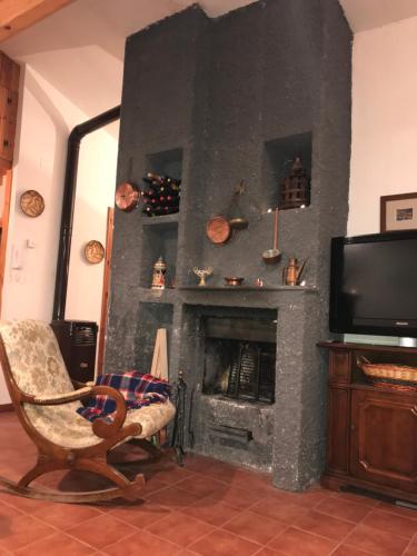 a living room with a fireplace with a chair and a television at In Mansarda Da Vanni in Rivisondoli