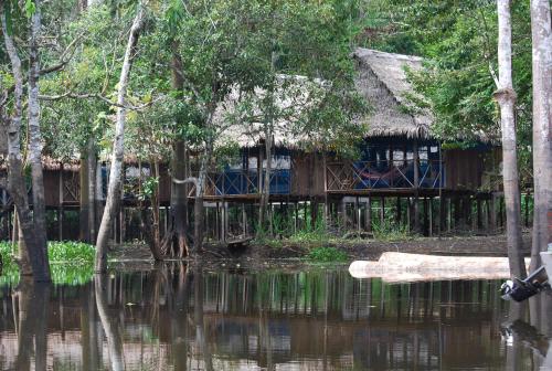a house on the water with trees in front of it at Amazon Muyuna Lodge - All Inclusive in Paraíso