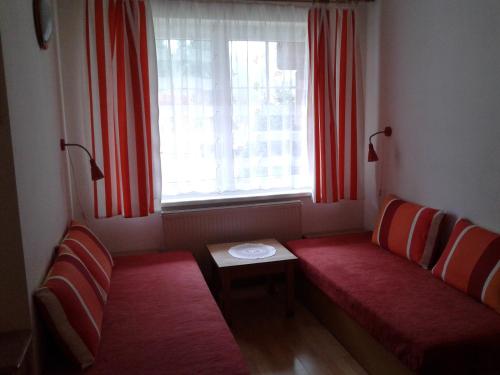 ハルラホフにあるAPARTMÁN GALERIEのベンチ2台、赤いカーテン付きの窓が備わる客室です。