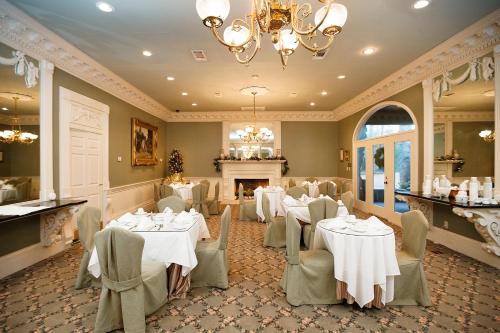 een restaurant met witte tafels en stoelen en een open haard bij Monmouth Historic Inn in Natchez