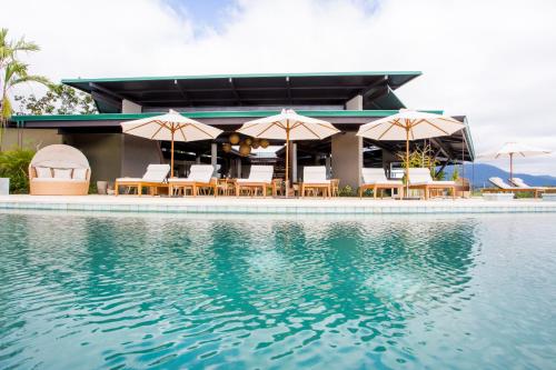 a resort with chairs and umbrellas next to a swimming pool at Hotel Three Sixty - Adults Only in Ojochal