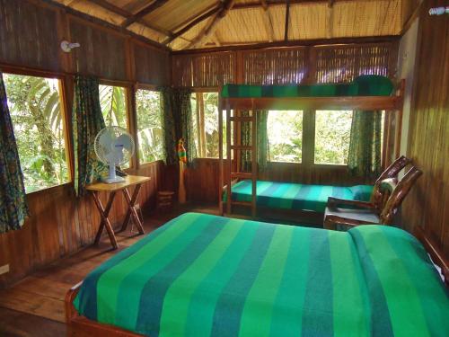 a bedroom with a green and blue bed and windows at Hosteria El Paraiso de las Orquideas in Archidona