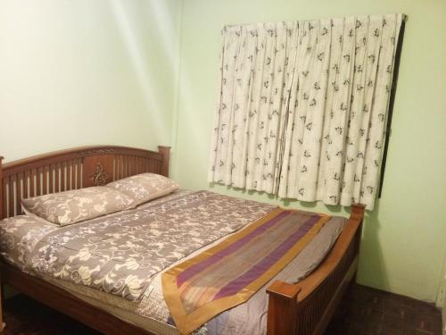 Un dormitorio con una cama y una ventana con cortinas. en Garden Homestay, en Suratthani