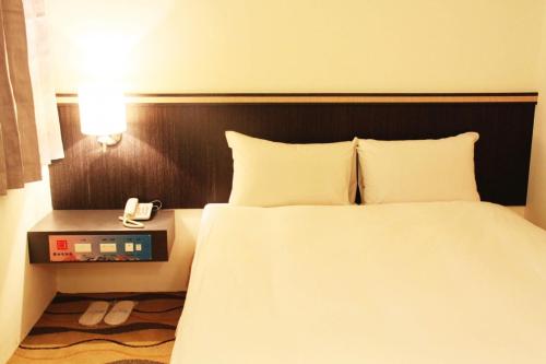 a bedroom with a bed and a phone on a table at Foung Gu Hotel in Magong