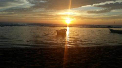 a boat sitting in the water with the sun setting at Paradise Bay in Beruwala