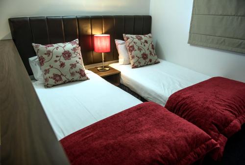 two beds in a room with a lamp on a table at The Park Hotel Ruapehu in National Park