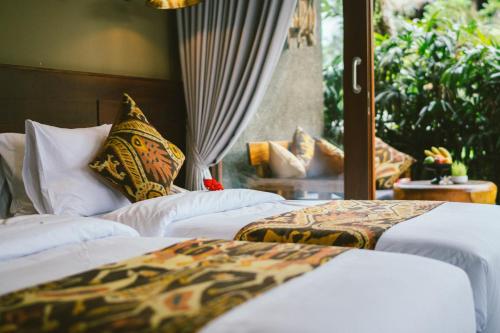 a bed room with two beds and two lamps at Honai Resort in Ubud