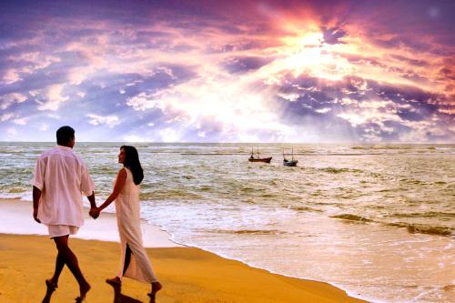 a man and a woman walking on the beach at Earl's Reef in Bentota