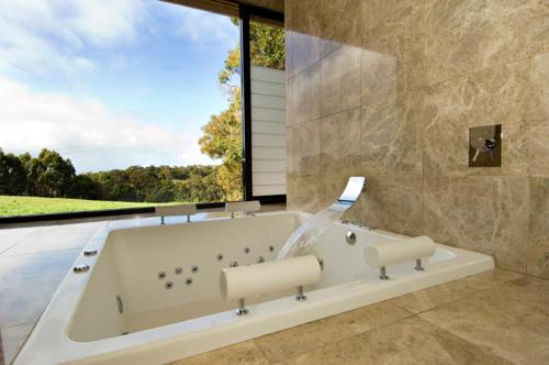 a bath tub in a bathroom with a large window at Chandeliers on Abbey in Yallingup