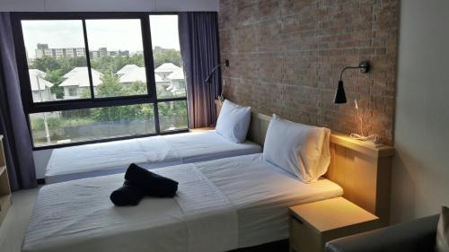 a bedroom with two beds and a large window at Bangkok Boutique Resort Rangsit in Pathum Thani
