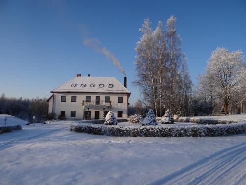 a large white building in the snow with christmas trees at Šubrakkrasti in Vestiena