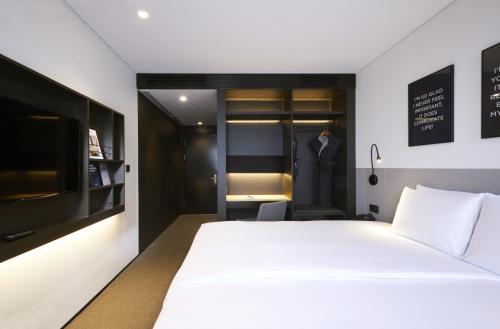 a bedroom with a white bed and a suit in a closet at GLAD Gangnam COEX Center in Seoul