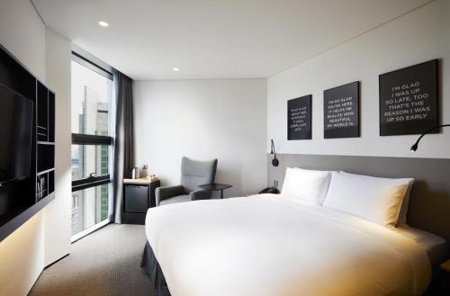 a bedroom with a large white bed and a window at GLAD Gangnam COEX Center in Seoul