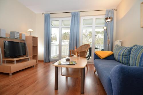 a living room with a blue couch and a table at Villa Seerose - Appartement 18 in Ostseebad Sellin