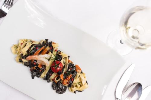 a plate of pasta with vegetables on a table at Hotel Winzerhof in Termeno