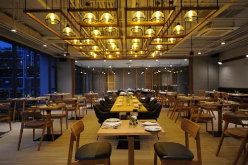 un restaurant avec des tables et des chaises et un grand lustre dans l'établissement Oakwood Hotel & Residence Sriracha - SHA Extra Plus, à Si Racha