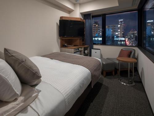 ein Hotelzimmer mit einem Bett und Stadtblick in der Unterkunft HOTEL MYSTAYS Midosuji Honmachi in Osaka