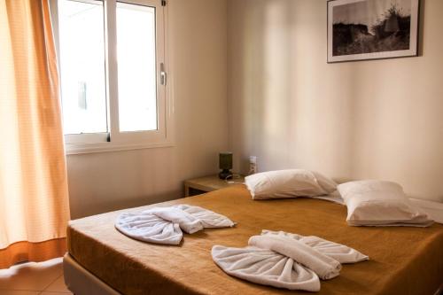 Argo Apartments Rethymno في مدينة ريثيمنو: غرفة نوم مع منشفتين على سرير مع نافذة