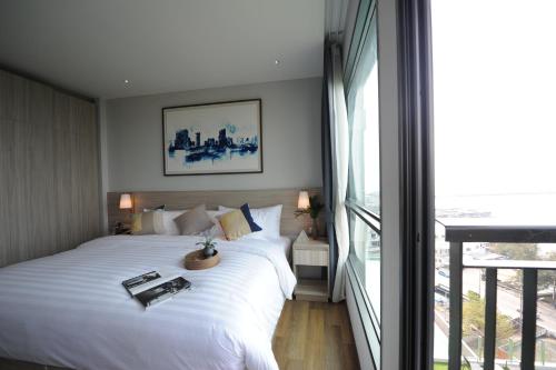 a bedroom with a large white bed and a large window at Oakwood Hotel & Residence Sri Racha in Si Racha