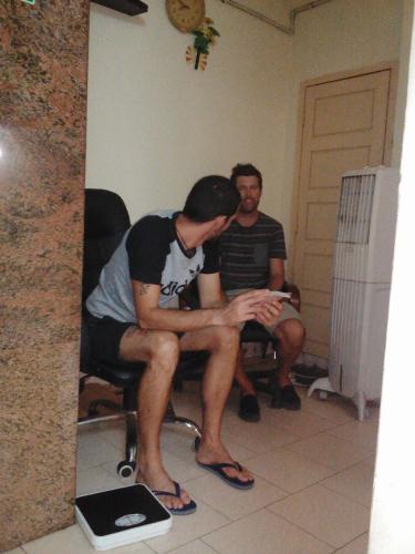 two men sitting in chairs looking at themselves in a mirror at St. Antonys Lodge in Cochin