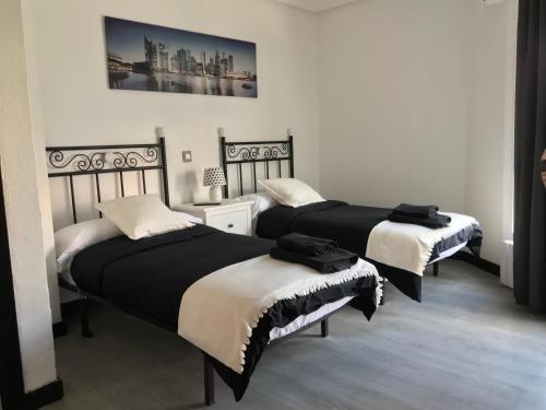 a bedroom with two beds and a picture on the wall at Alojamiento El Cantal in Santoña