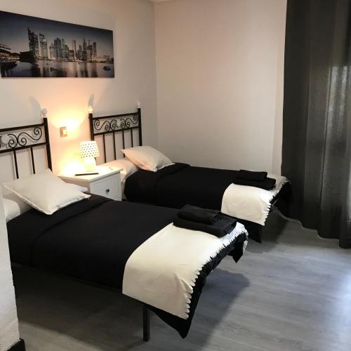three beds in a room with black and white at Alojamiento El Cantal in Santoña