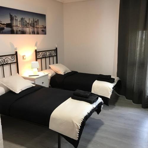 a bedroom with two beds and a table with a lamp at Alojamiento El Cantal in Santoña