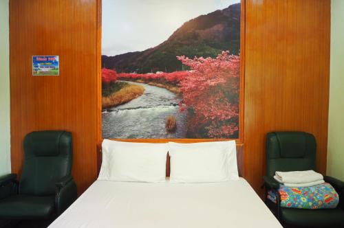 a bed in a room with a painting of a river at 555 Resort in Udon Thani