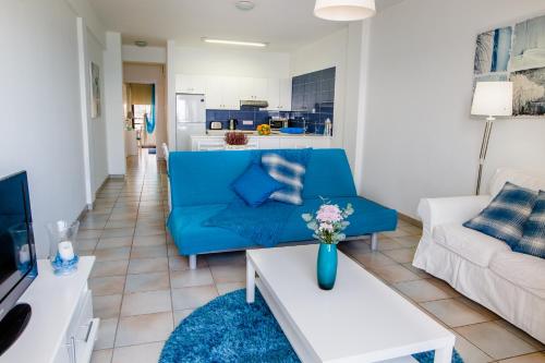 a living room with a blue couch and a table at Krasas Beach Apts in Larnaka