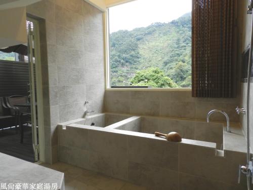 a bath tub in a bathroom with a window at 谷關明高溫泉 Mingao Hot Spring Resort in Heping