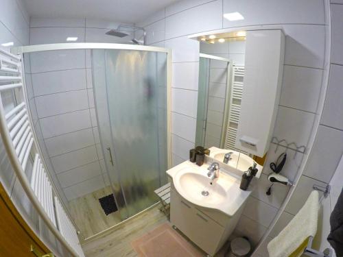 a white bathroom with a sink and a shower at Apartmani Oletić 4* in Sveti Martin na Muri