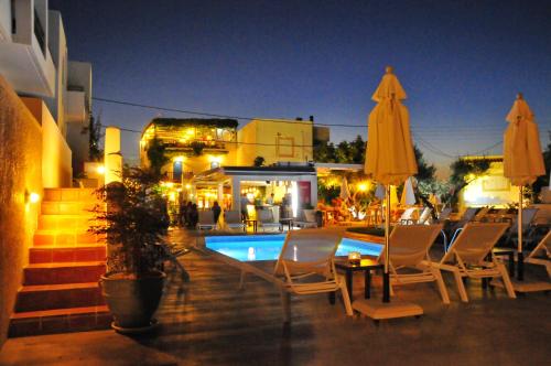 a pool with chairs and umbrellas at night at Casa Bianca Adults Only "by Checkin" in Hersonissos