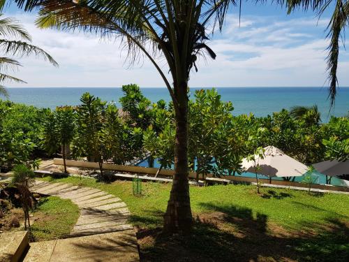 a palm tree and a walkway near the ocean at Rumassala Villas in Unawatuna