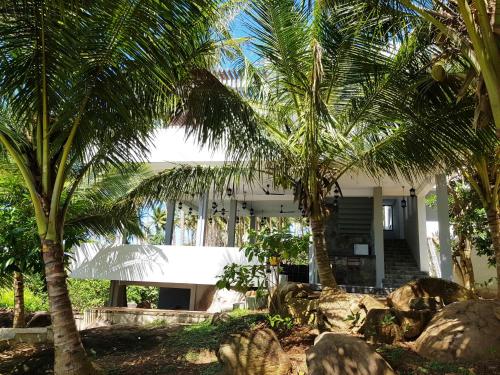 a white house with palm trees in front of it at Rumassala Villas in Unawatuna