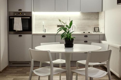 a white table with white chairs and a potted plant at Old Town Trio Apartments in Vilnius