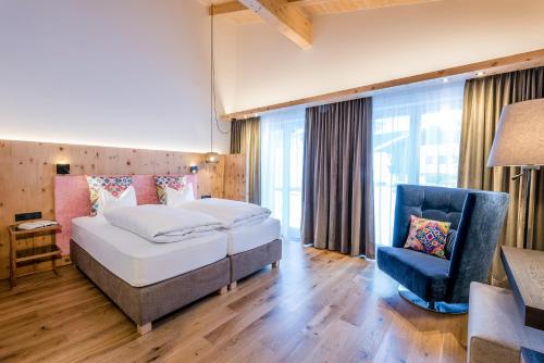 una habitación de hotel con 2 camas y una silla en "Quality Hosts Arlberg" Hotel zur Pfeffermühle, en Sankt Anton am Arlberg