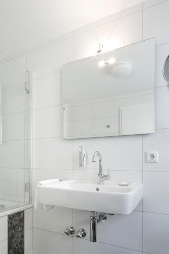 a white bathroom with a sink and a shower at Zu den Drei Linden - Hotel & Restaurant in Wermelskirchen
