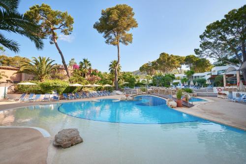 una gran piscina con sillas y palmeras en Hipotels Eurotel Punta Rotja Spa-Golf, en Costa des Pins