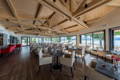 une salle à manger avec tables, chaises et fenêtres dans l'établissement Les Terrasses Du Lac, à Langogne