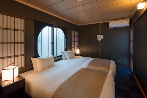 a bedroom with a large white bed with windows at Fujinoma Machiya House in Kyoto