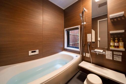 a bathroom with a tub and a toilet and a sink at Fujinoma Machiya House in Kyoto
